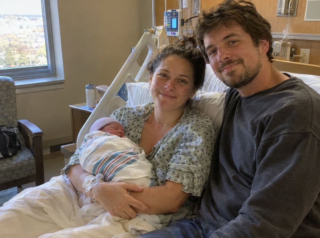 A new mother and father with their newborn in a hospital room